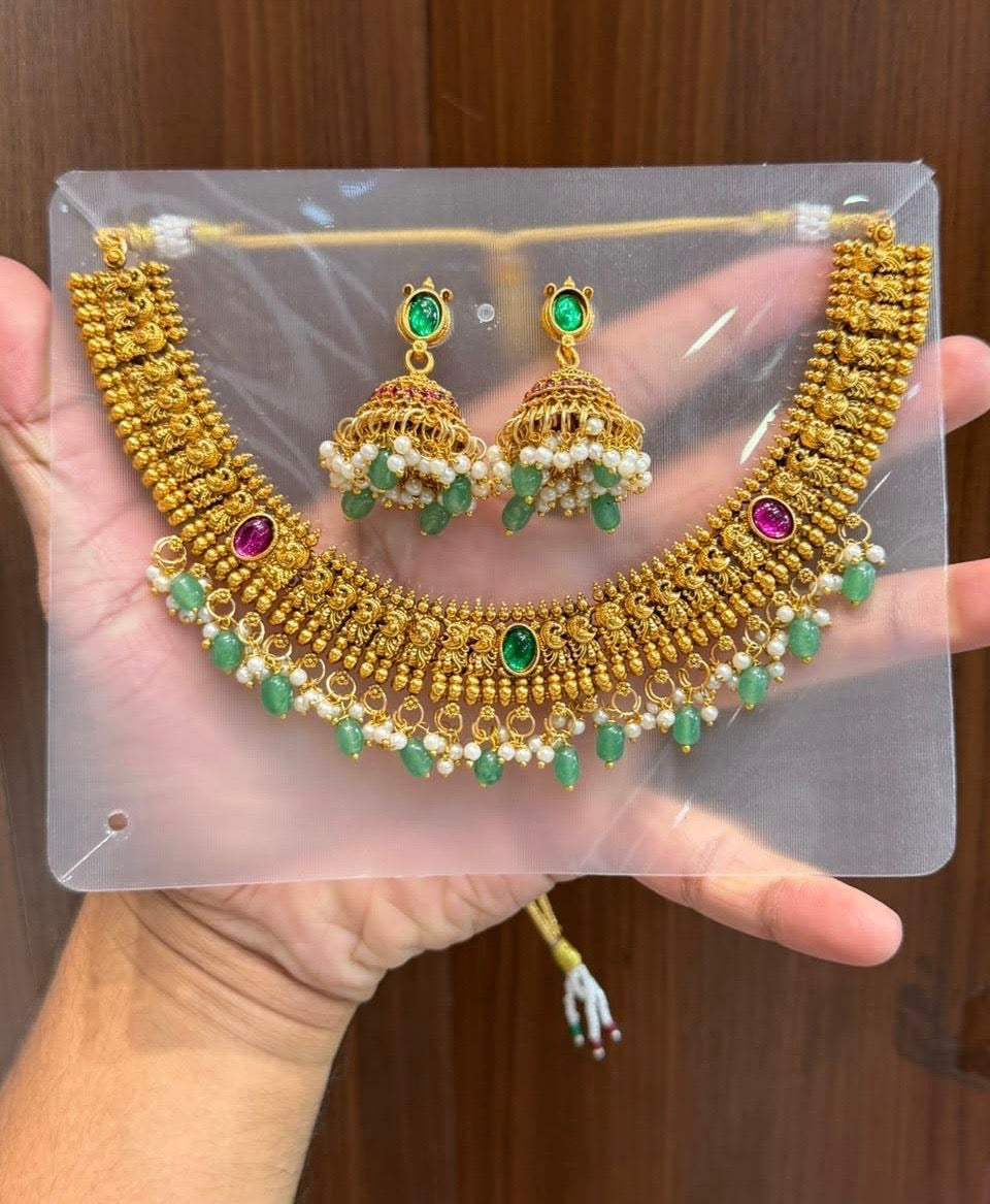 Premium traditional South Indian gold-plated temple jewelry necklace and jhumka earring set adorned with green and ruby-colored stones and pearl drops product code T143