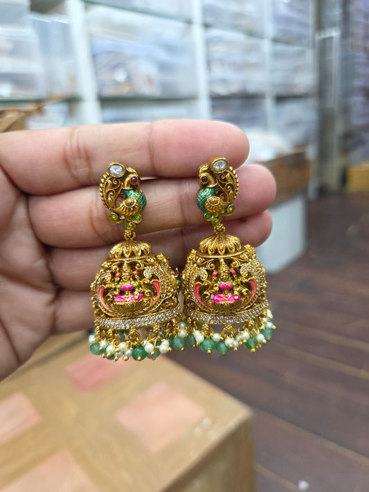 Premium antique-finish Lakshmi temple jhumka earrings with intricate peacock studs, ruby and green stone accents, and delicate pearl drops product code E190
